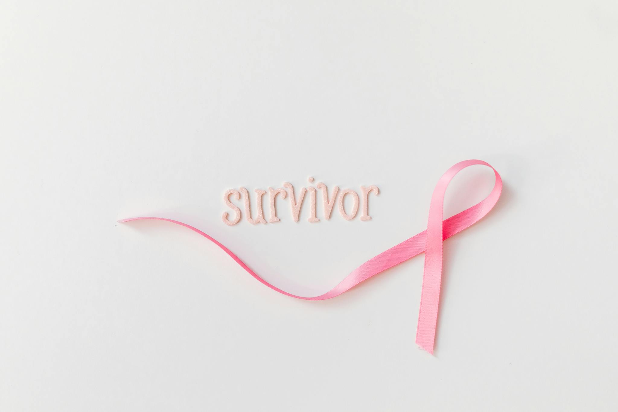 Pink ribbon next to 'survivor' text symbolizing breast cancer awareness and hope.